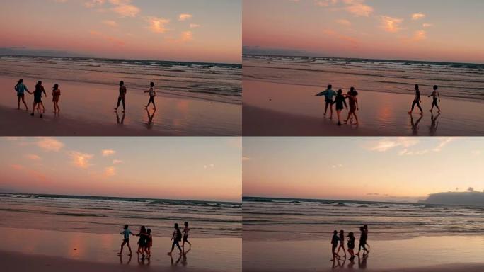 青少年朋友在日落时在海滩上散步
