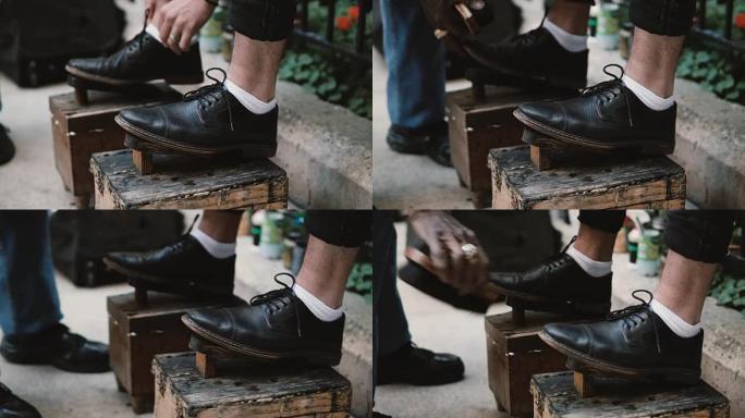 看台上男性脚的特写镜头。擦鞋匠在街上工作，在市区擦亮黑色鞋子