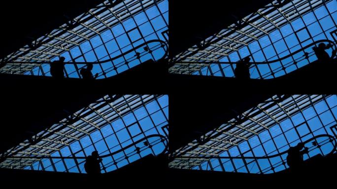 现代玻璃建筑和自动扶梯上商人的移动剪影
