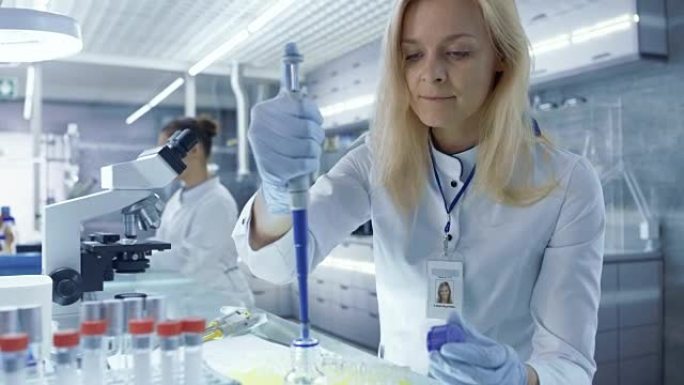 女性医学研究人员使用微量移液器。她测试分析。科学家们正在这个巨大的光实验室工作