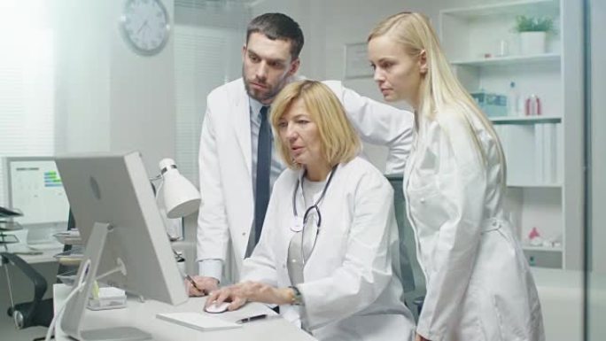 由三名医学专家组成的小组在台式计算机上解决问题。他们打手势并指向屏幕。