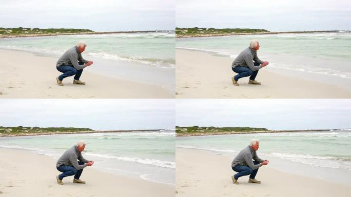 退休男子跪在沙滩上眺望大海