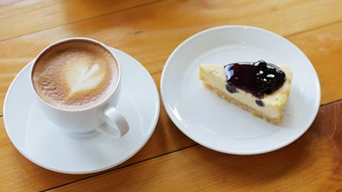 蓝莓奶酪派，带拿铁艺术咖啡，放在木制桌子上，放松概念，多莉射击