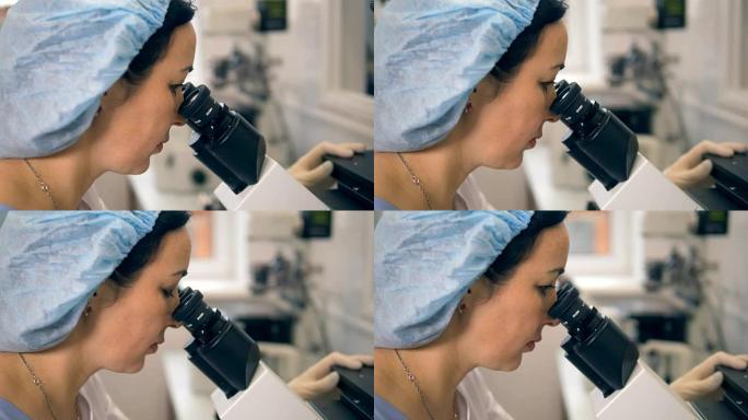 一个女人在显微镜下看目镜的近距离观察。