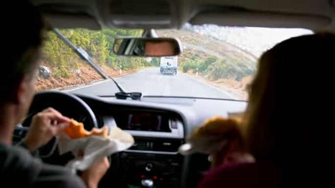 女士夫妇在雨天路上吃饭和开车，享受公路旅行