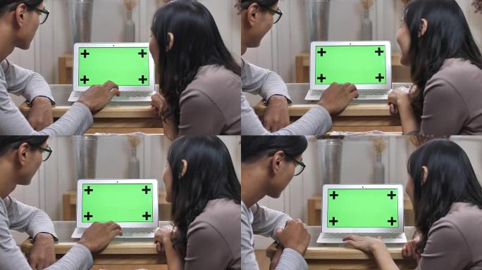 两个人看着绿屏的笔记本电脑