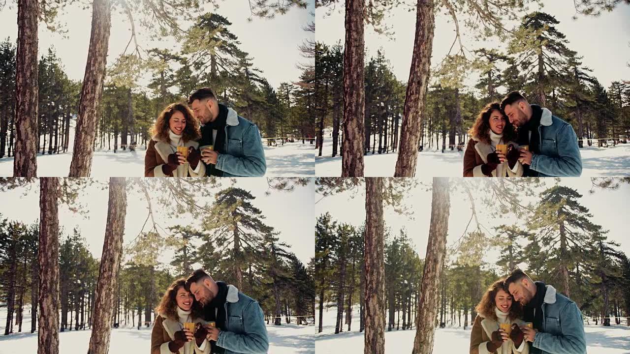 在下雪的冬日，情侣拥抱和喝热饮料