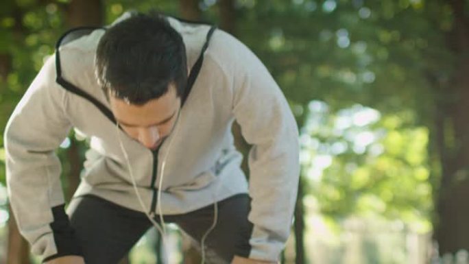 疲惫的男性慢跑者在晨跑时停下来喘口气。