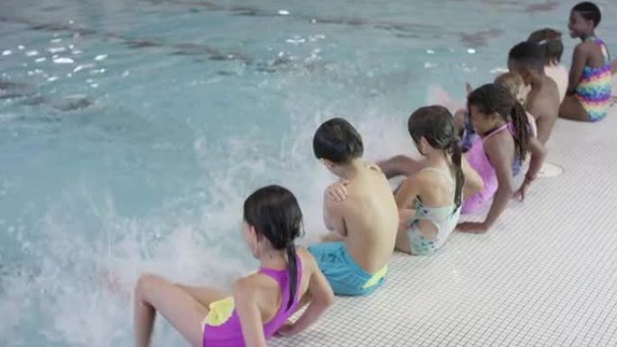 多种族的儿童在游泳池里踢腿
