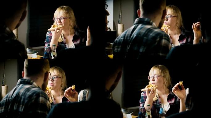 年轻漂亮的戴眼镜的欧洲女孩喜欢吃披萨，和朋友在休闲派对上聊天