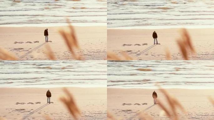 一个用脚在美丽海滩的沙滩上用俄语写朱莉娅的家伙的远景
