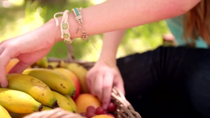 女人的手从水果篮里拿香蕉