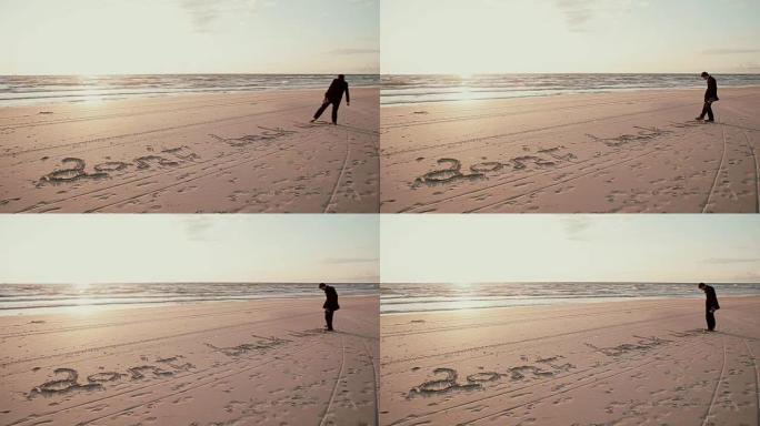 日落时，一个穿着黑色外套的年轻人正在沙滩上写 “不要回去”