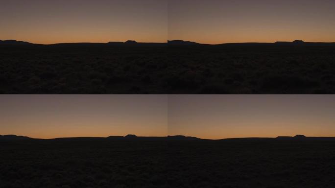 空中低角度:在日出前的黎明时分，在茂密的沙漠上空低空飞行