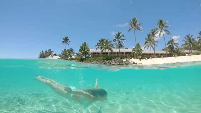 半水下: 年轻女子在热带岛屿度假期间游泳。