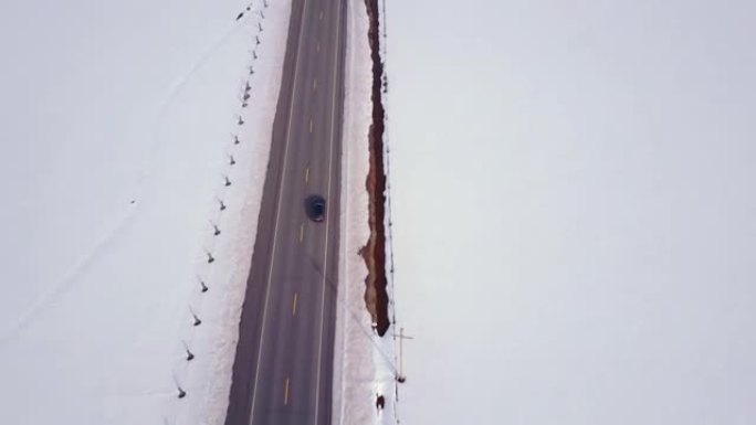 空中4K: 汽车在高速公路上穿越积雪覆盖的田野
