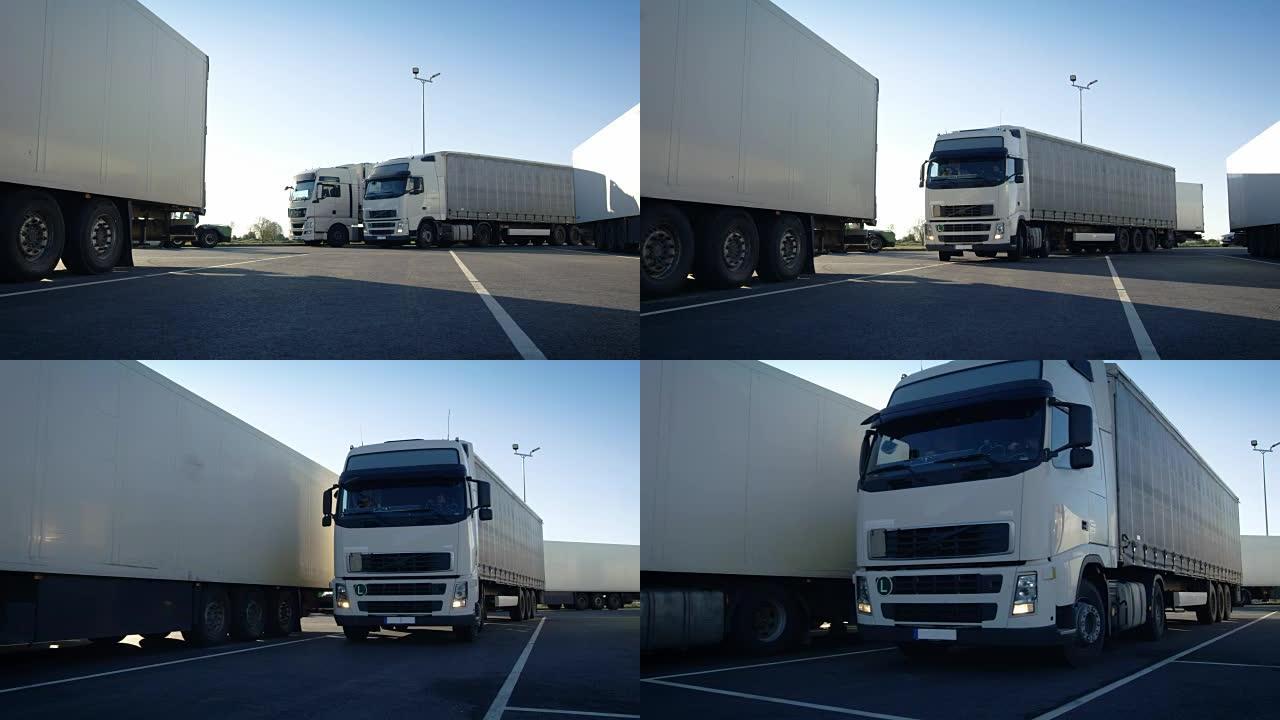 带有货运拖车的白色半卡车驶入停车场，并与其他车辆一起停放。