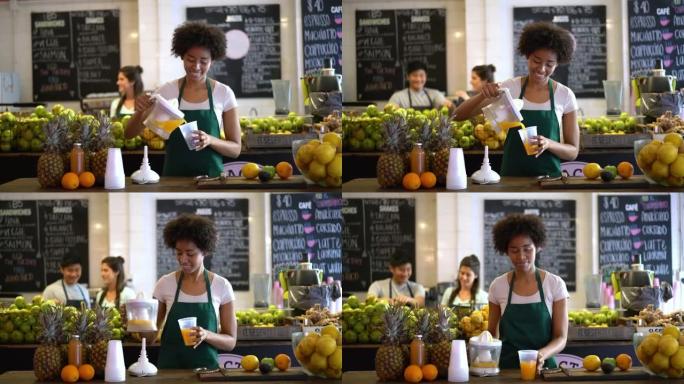 多元化的团队在果汁吧工作，前面的女人用电动榨汁机制作果汁，然后看着相机