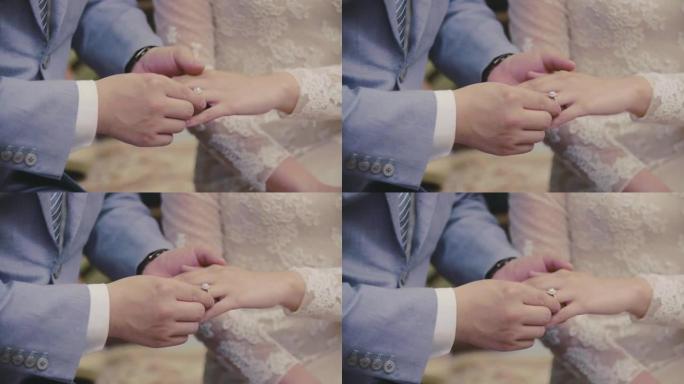 新郎在婚礼订婚时把戒指戴在新娘的手指上。