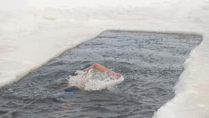 一个戴着银帽的人在冰洞里游泳。