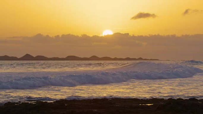 慢动作: 当太阳落在云层后时，反射的小海浪破裂。
