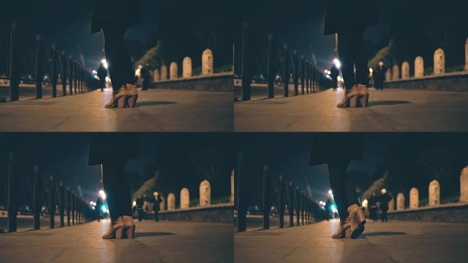 女性腿穿高跟鞋的特写镜头。女人晚上站在桥上等待