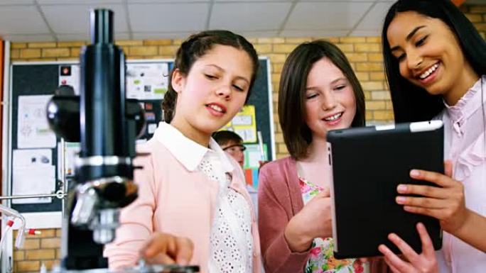 微笑的女学生在实验室讨论数字平板电脑