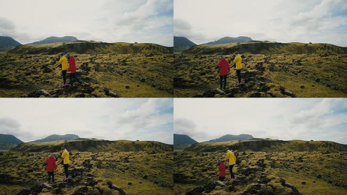 在冰岛的熔岩场上行走的游客的鸟瞰图。两个女人在山上徒步旅行，享受爱好