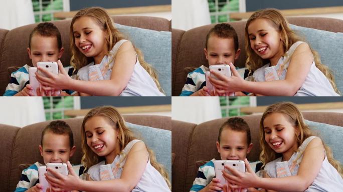 微笑的男孩和女孩坐在沙发上使用手机