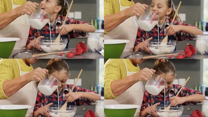 女孩一边搅拌面粉，一边奶奶把牛奶倒进碗里4K 4k