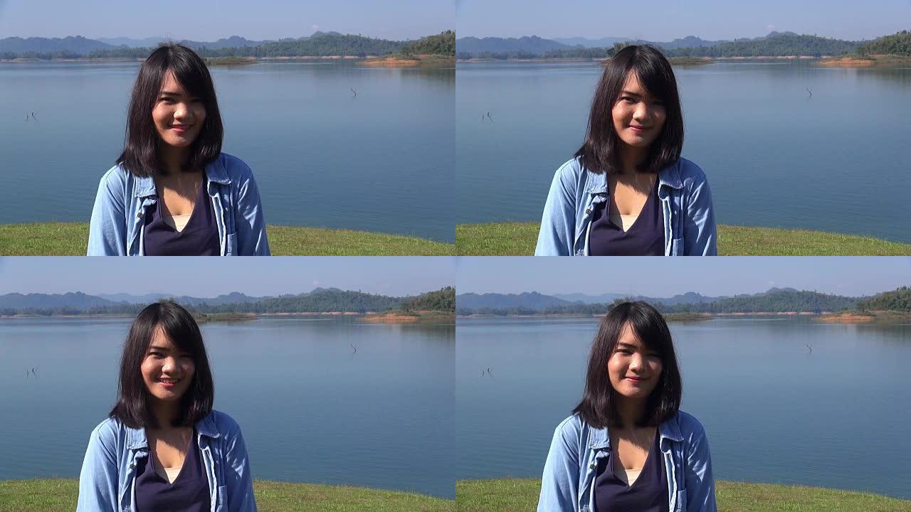 年轻女子站在湖边，看着镜头微笑。