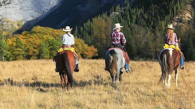 牛仔和两个牛仔女孩朝着山骑行