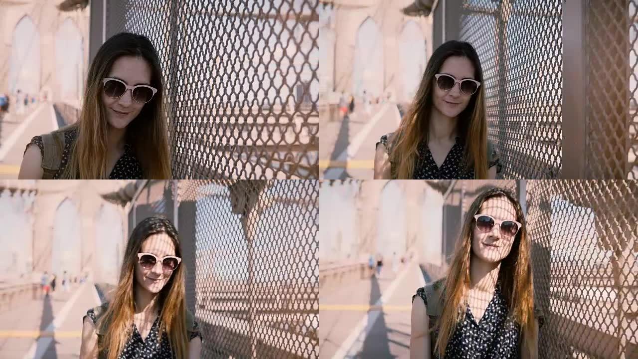 戴着墨镜的美丽女游客微笑着，靠在布鲁克林大桥的阴影网围栏上，走向相机4K