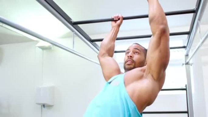 肌肉发达的年轻人在健身房的猴子酒吧锻炼