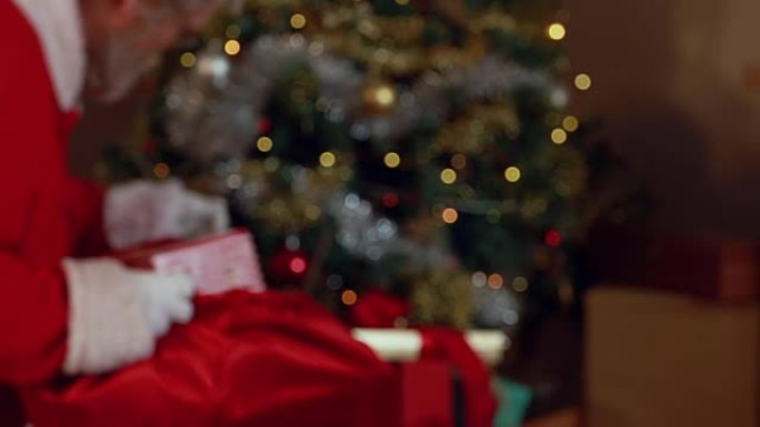 手指放在嘴唇上的圣诞老人把礼品盒放在圣诞袋里