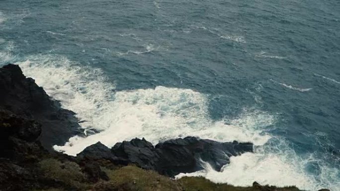 特写海景。泡沫在岸上飞溅的波浪，在黑色的岩石上