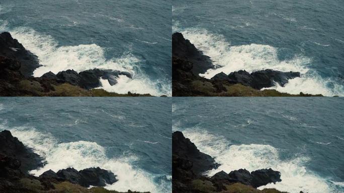 特写海景。泡沫在岸上飞溅的波浪，在黑色的岩石上