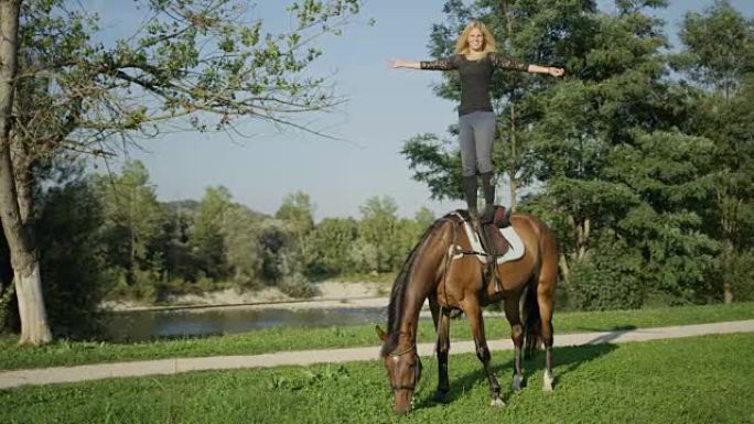 特写: 女骑手伸出双臂站在马背上