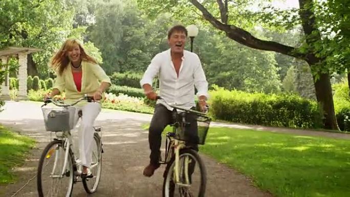 快乐的成年夫妇在公园骑自行车。