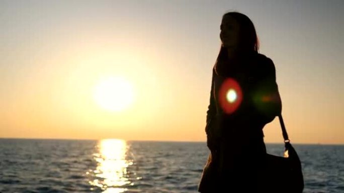 日落时在海边散步的年轻女子