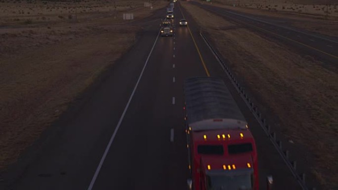 空中: 黄昏时沿高速公路行驶的货运半卡车和汽车的交通