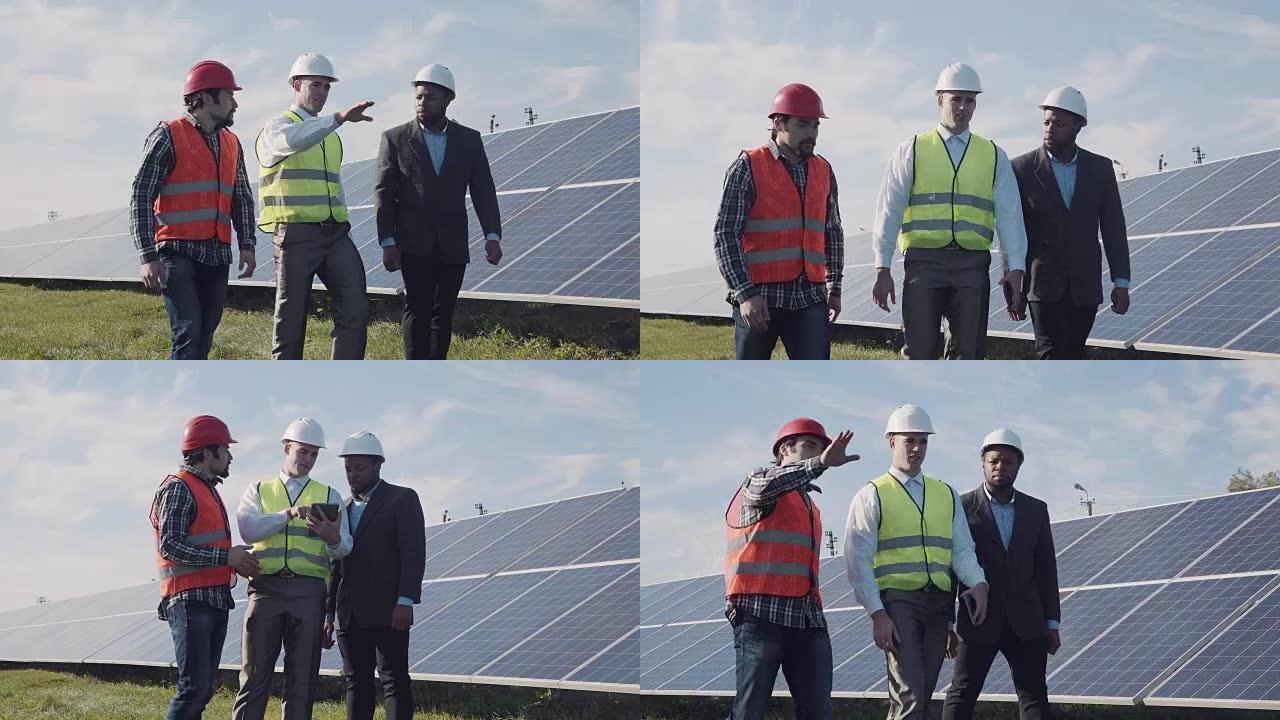 工人走在一排排太阳能电池板之间