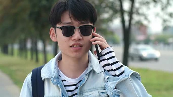 十几岁的亚洲男孩在街上用手机聊天