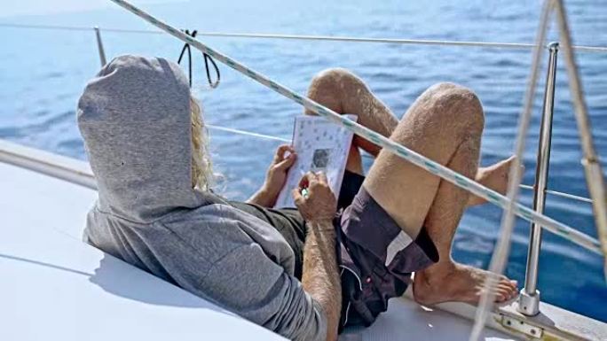 4k男子放松，在阳光帆船上做填字游戏，实时