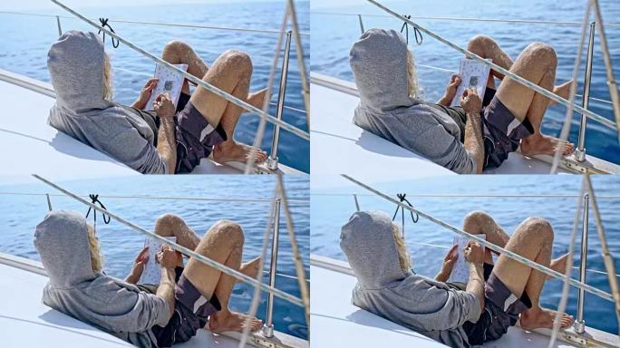 4k男子放松，在阳光帆船上做填字游戏，实时