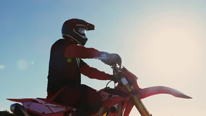 低角度镜头的职业摩托车越野赛骑手在FMX摩托车站在采石场中间，俯瞰极端越野地形，他今天要骑。
