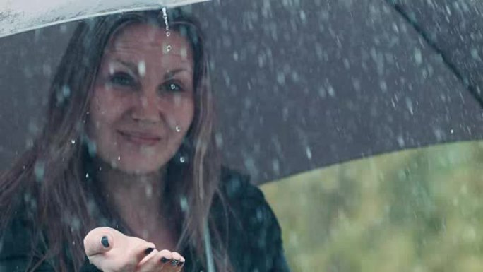 雨伞下的金发女人打着雨滴