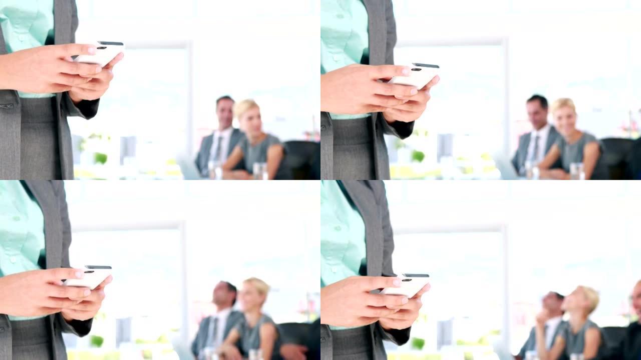 女商人在后台与同事在手机上发短信