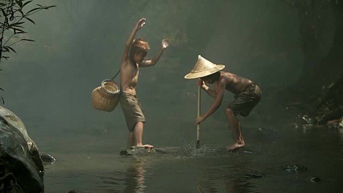两个亚洲男孩正在池塘边快乐地钓鱼。