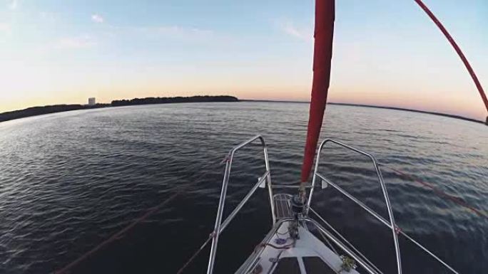 帆船鼻部的特写镜头穿过水。日落时，晴天在公海风中航行